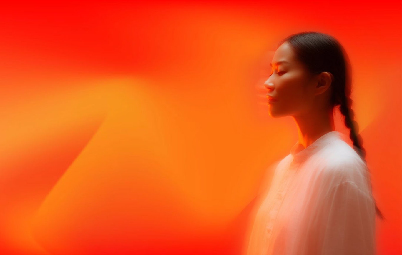 Woman in profile against a glowing orange gradient