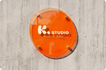 Orange K. Studio sign mounted on a concrete wall