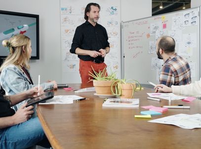 Team workshop around a conference table with sketches on the whiteboards