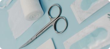 Surgical scissors and bandages on a blue surface