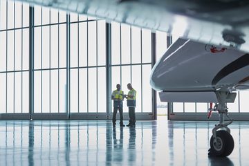 Two technicians beside a business jet in a hangar