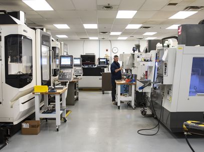 Machine shop with CNC machining centers and an engineer at a workstation